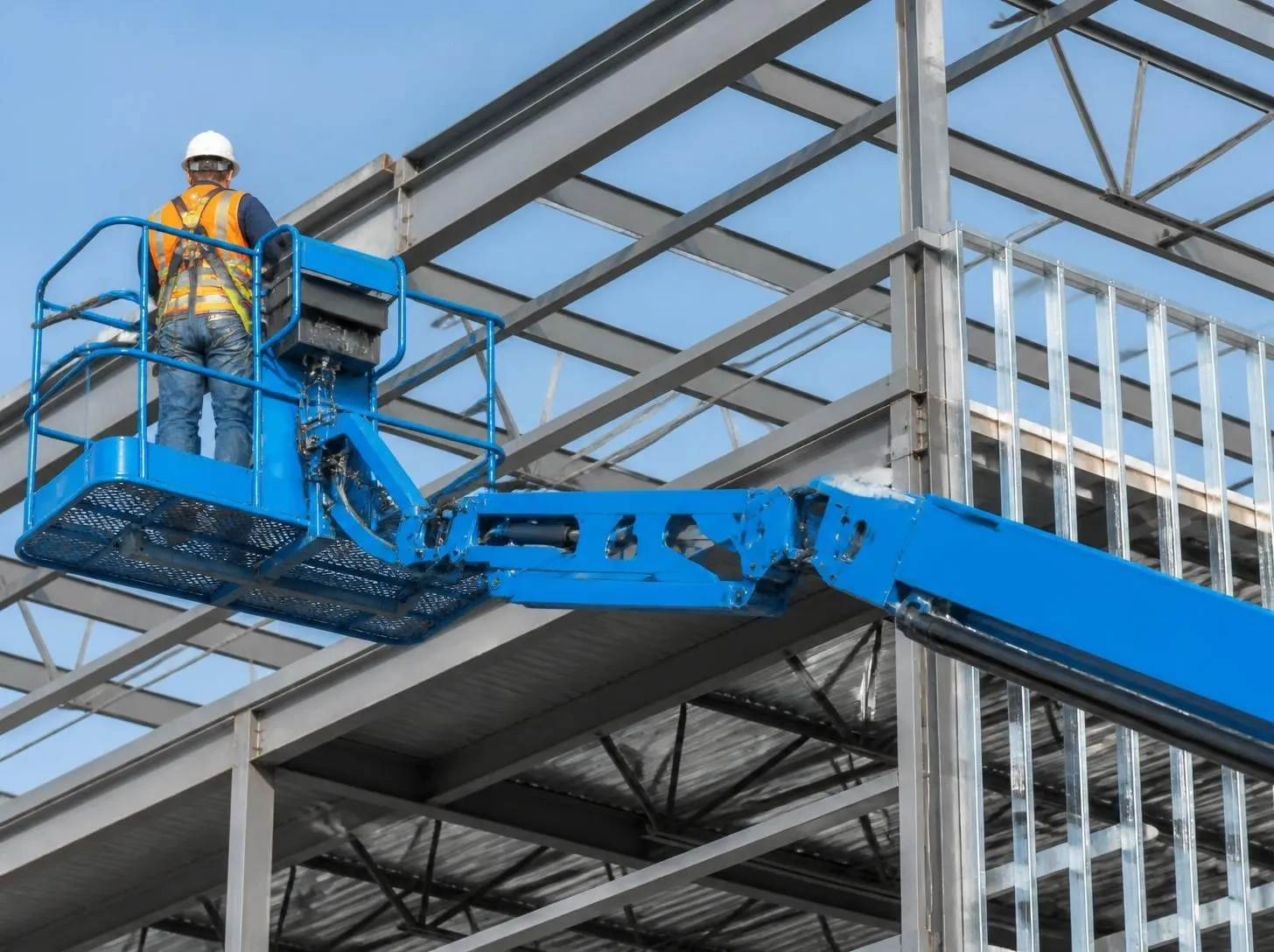 Articulated boom lift extended against a steel-frame building under construction