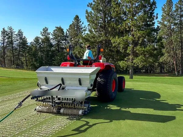Turf care equipment aerating a golf course green
