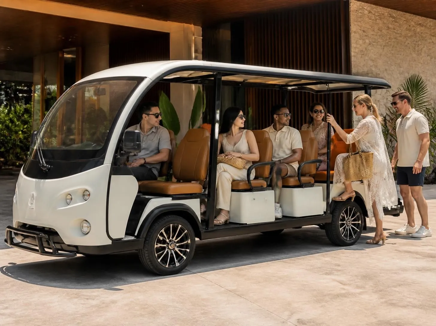 Guests boarding a white electric resort shuttle outside a luxury hotel entrance