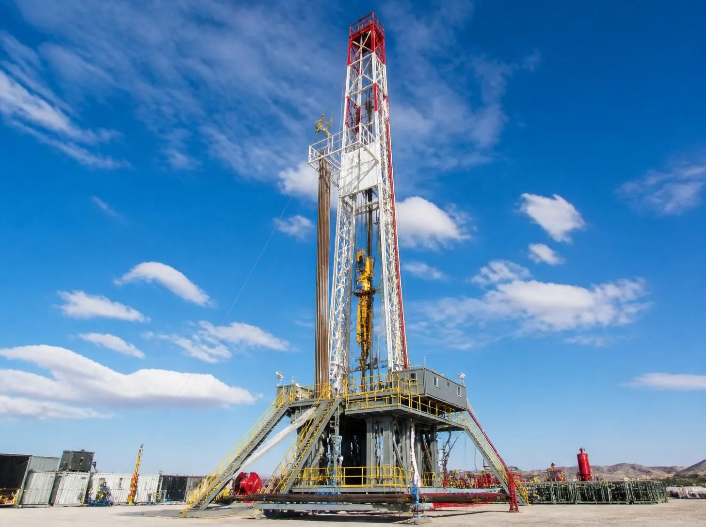 Land drilling rig mast standing on an active wellsite