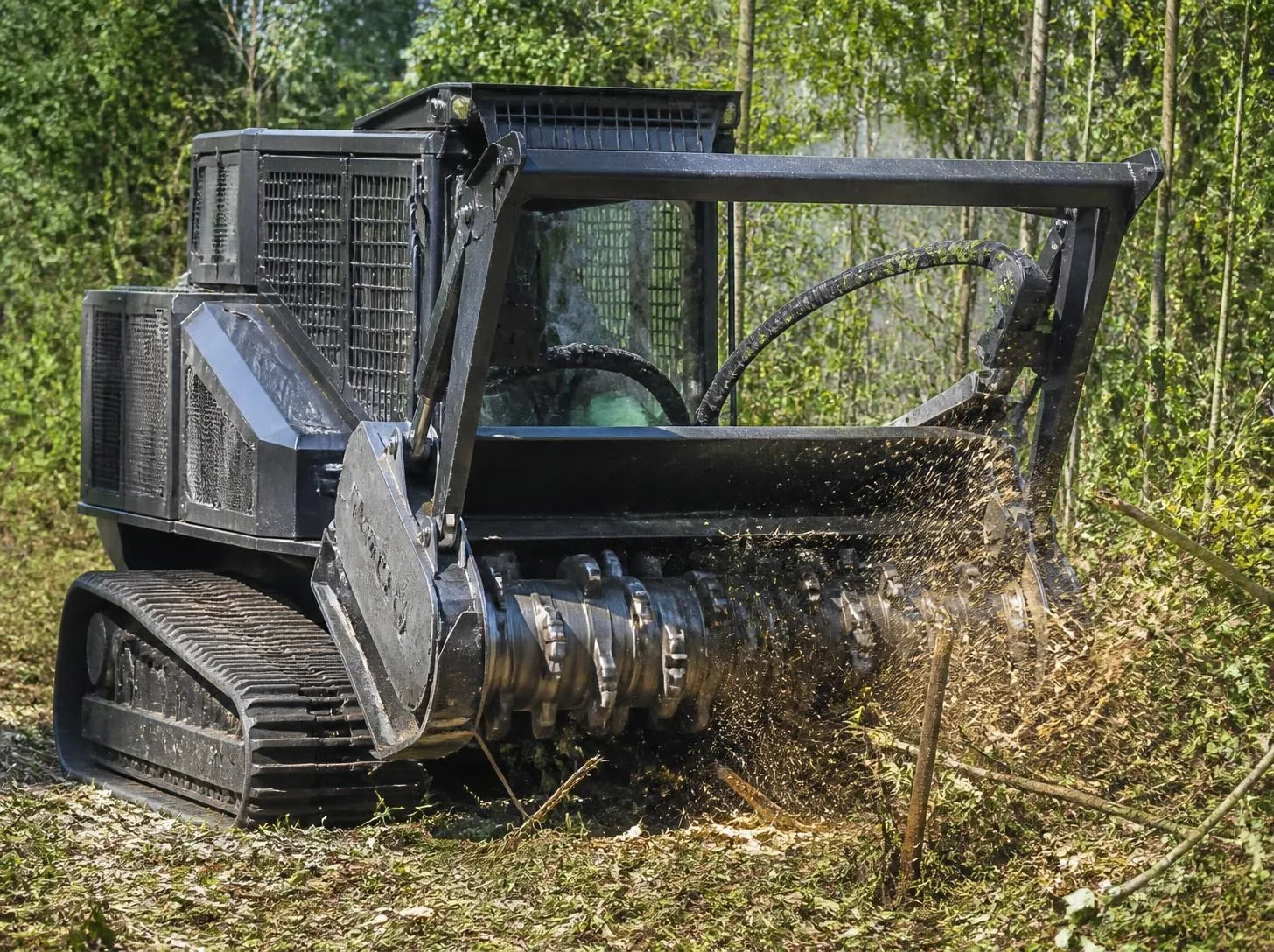 Tracked forestry mulcher clearing brush with its rotating mulching head
